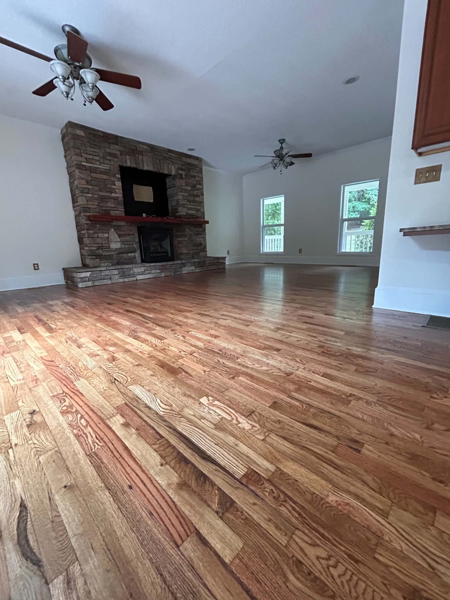 Hardwood floor in a living room with a stone fireplace